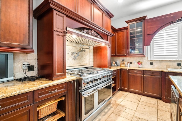 kitchen with range with two ovens, tasteful backsplash, glass insert cabinets, dark brown cabinets, and light stone countertops