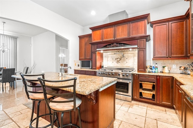 kitchen featuring arched walkways, a notable chandelier, a sink, stainless steel range, and stone tile flooring