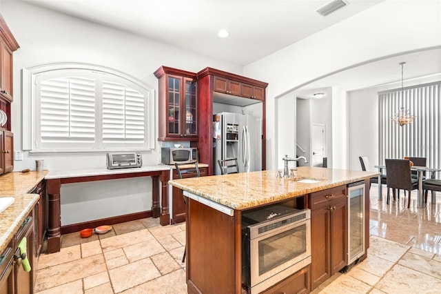 kitchen with light stone counters, wine cooler, visible vents, appliances with stainless steel finishes, and a sink