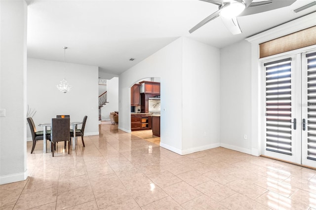 dining area with arched walkways, ceiling fan with notable chandelier, visible vents, baseboards, and stairway