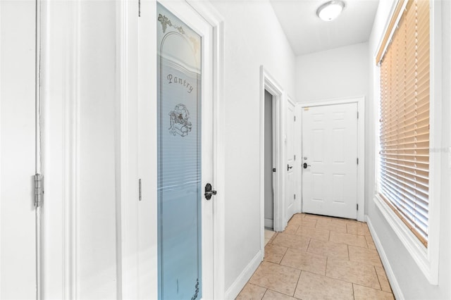 corridor featuring light tile patterned floors and baseboards