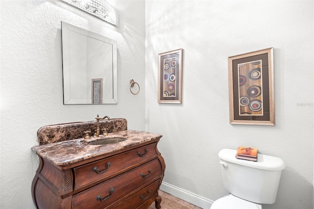 bathroom with toilet, vanity, and baseboards