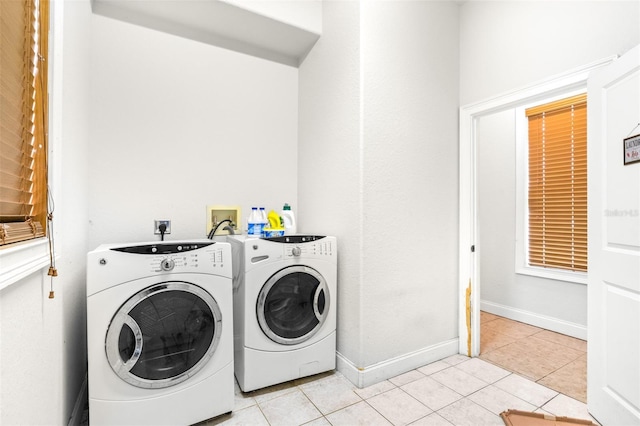 clothes washing area featuring washing machine and dryer, laundry area, light tile patterned flooring, and baseboards