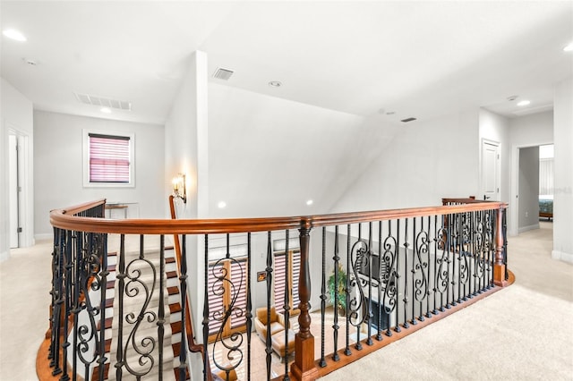 hall with an upstairs landing, carpet flooring, visible vents, and baseboards