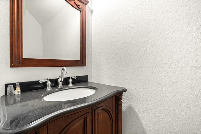 bathroom with a textured wall and vanity