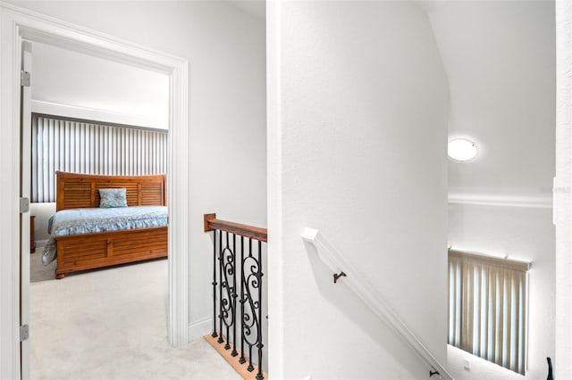 hall with an upstairs landing and light colored carpet