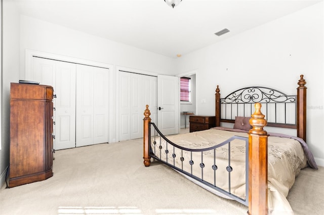 bedroom featuring carpet, two closets, and visible vents