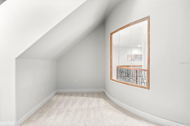bonus room with baseboards, vaulted ceiling, and light colored carpet