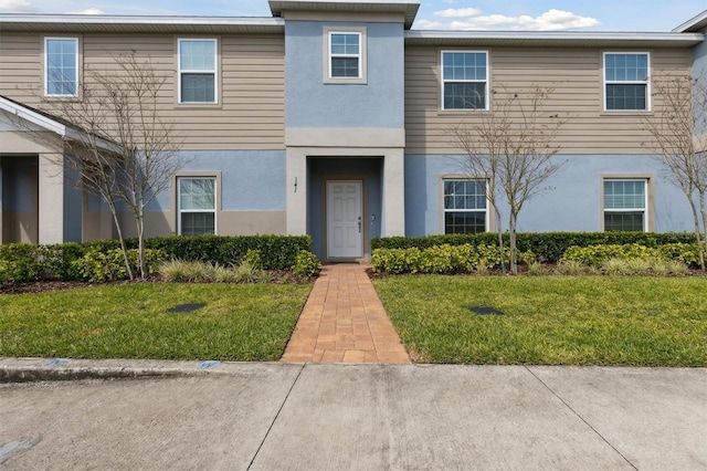 view of property featuring a front lawn and stucco siding