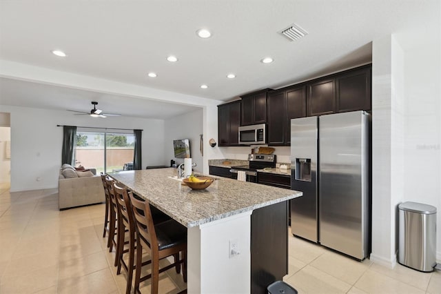 kitchen with a kitchen island with sink, recessed lighting, stainless steel appliances, visible vents, and a kitchen breakfast bar