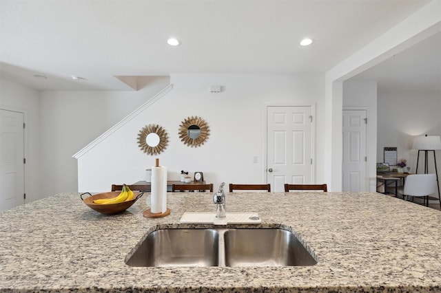 kitchen with light stone countertops, a sink, and recessed lighting