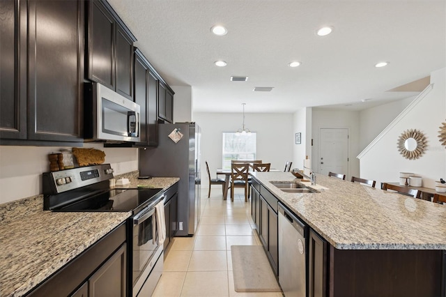 kitchen with light tile patterned floors, a center island with sink, visible vents, stainless steel appliances, and a sink