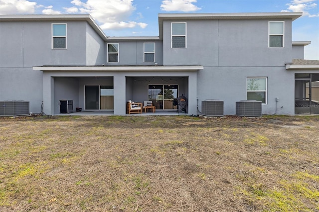 rear view of house featuring stucco siding, cooling unit, and a patio