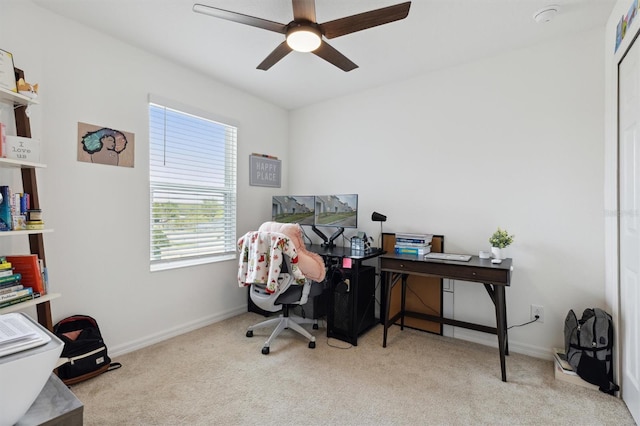 carpeted office space featuring ceiling fan and baseboards