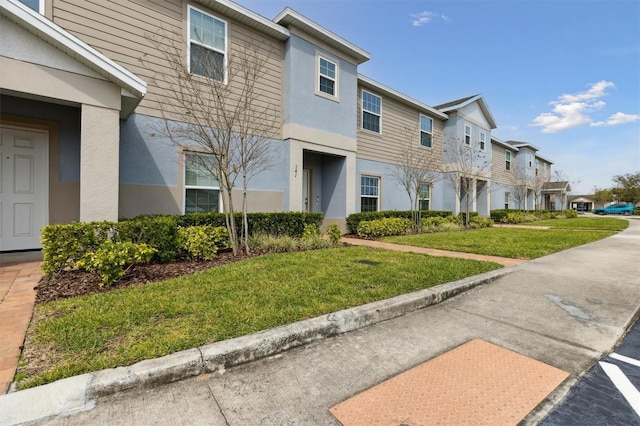 view of front of home featuring a front lawn, a residential view, and stucco siding