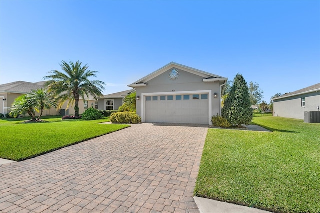 ranch-style home featuring a front yard, decorative driveway, an attached garage, and central AC unit