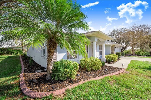 view of side of home featuring an attached garage, a yard, concrete driveway, and stucco siding