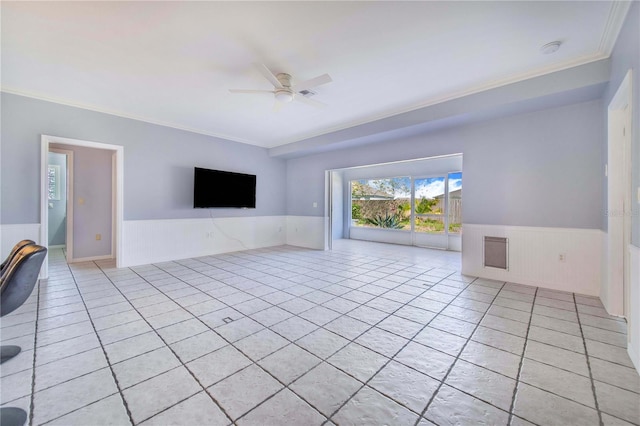 unfurnished living room featuring light tile patterned floors, crown molding, a ceiling fan, and wainscoting