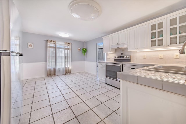 kitchen with stainless steel electric stove, tile counters, light tile patterned flooring, a sink, and under cabinet range hood