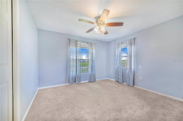 spare room with carpet floors, a ceiling fan, and baseboards