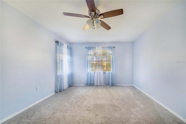 carpeted empty room featuring ceiling fan and baseboards