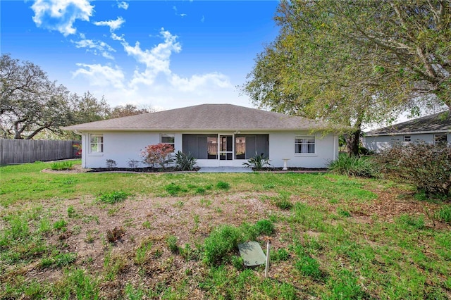 view of front facade featuring fence, a front lawn, and stucco siding