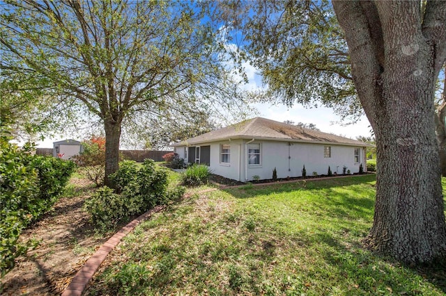 exterior space featuring an outbuilding, stucco siding, a yard, and fence