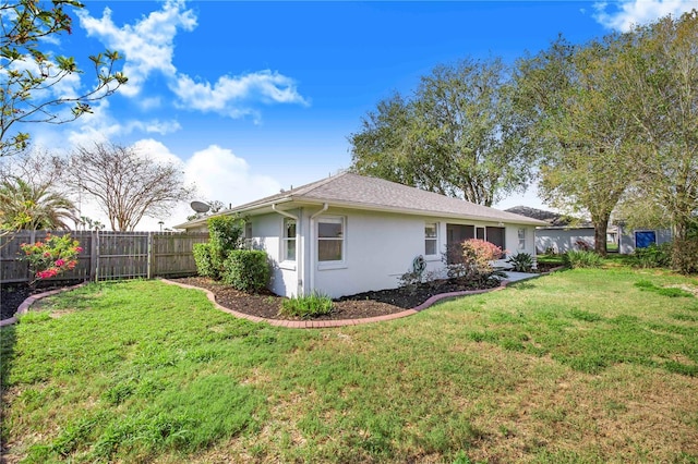 view of side of property featuring stucco siding, fence, and a yard