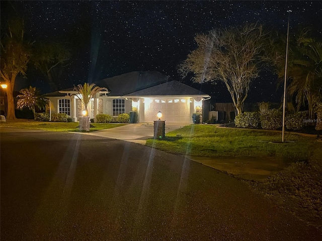 single story home with driveway, an attached garage, and a yard