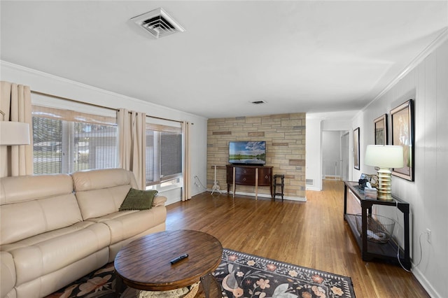 living area featuring wood finished floors, baseboards, visible vents, a fireplace, and ornamental molding