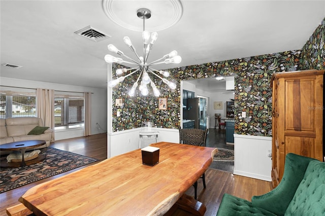 dining space featuring a wainscoted wall, an inviting chandelier, wallpapered walls, and visible vents