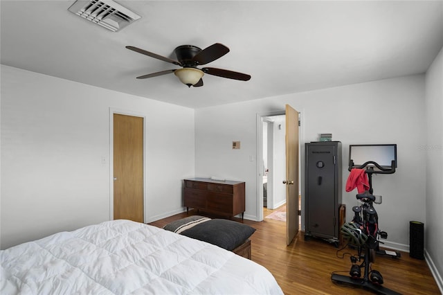 bedroom featuring visible vents, a ceiling fan, baseboards, and wood finished floors