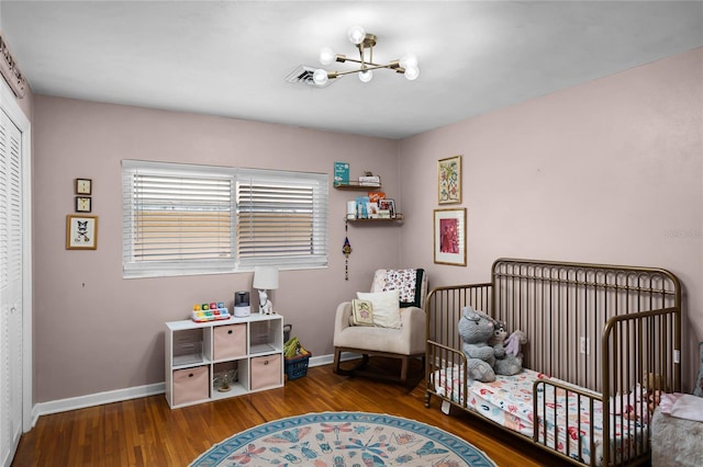 bedroom featuring wood finished floors, visible vents, a closet, and baseboards