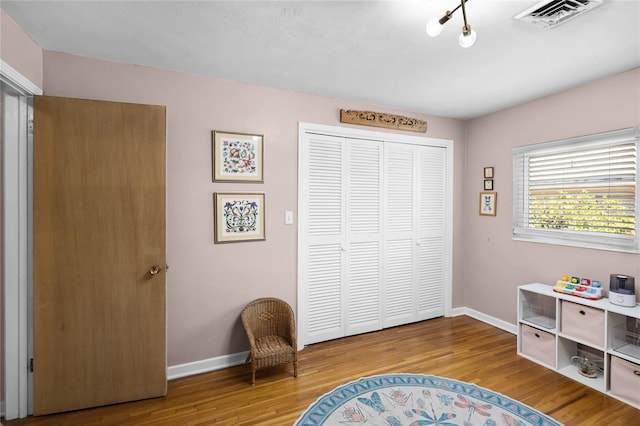 living area with visible vents, baseboards, and wood finished floors