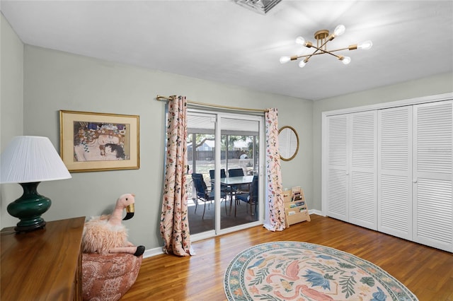 living area with visible vents, baseboards, wood finished floors, and a chandelier