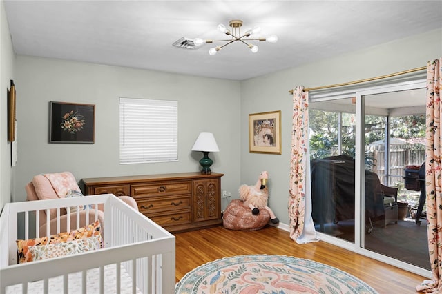 bedroom with access to exterior, visible vents, baseboards, a chandelier, and wood finished floors