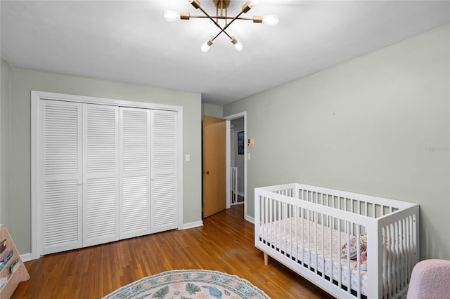 bedroom with a closet, a chandelier, baseboards, and wood finished floors