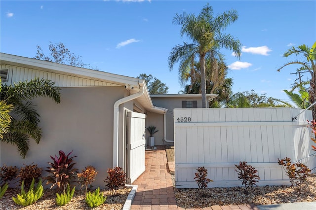 view of side of home featuring fence and stucco siding