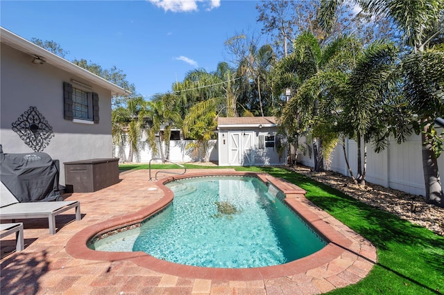 view of swimming pool with area for grilling, a patio, a fenced backyard, a storage unit, and an outdoor structure