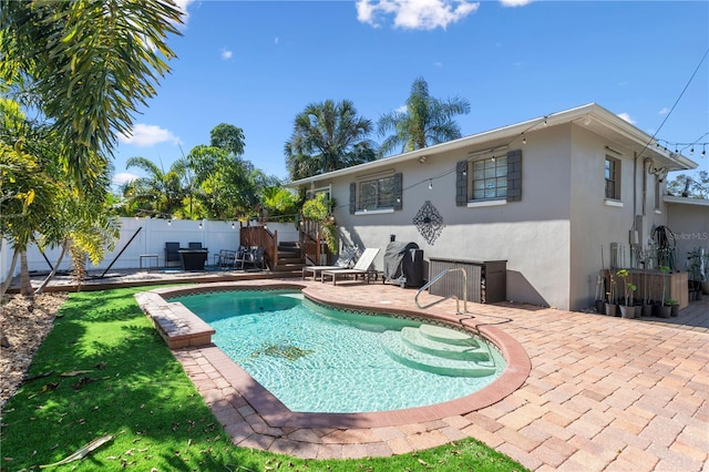 rear view of house featuring a patio area, fence, a fenced in pool, and stucco siding