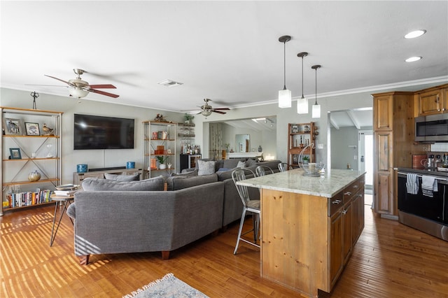 kitchen with wood-type flooring, visible vents, appliances with stainless steel finishes, and a breakfast bar