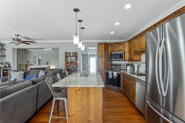 kitchen with appliances with stainless steel finishes, brown cabinets, a breakfast bar, open floor plan, and a sink