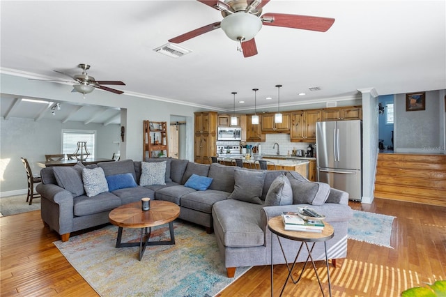 living room featuring visible vents, ornamental molding, ceiling fan, wood finished floors, and baseboards