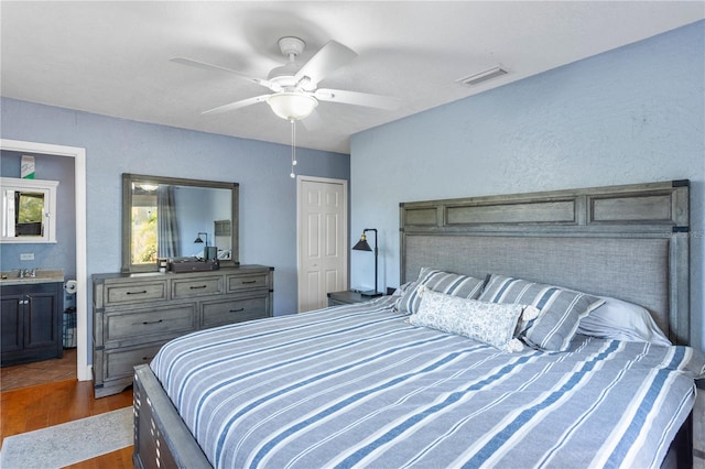 bedroom with a sink, dark wood-style floors, visible vents, and a ceiling fan