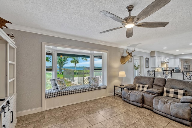 living area featuring a ceiling fan, a textured ceiling, crown molding, baseboards, and a textured wall