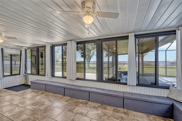 unfurnished sunroom featuring wooden ceiling, plenty of natural light, and a ceiling fan