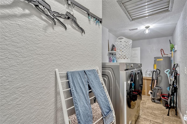 laundry room with laundry area, washing machine and dryer, electric water heater, and a textured wall