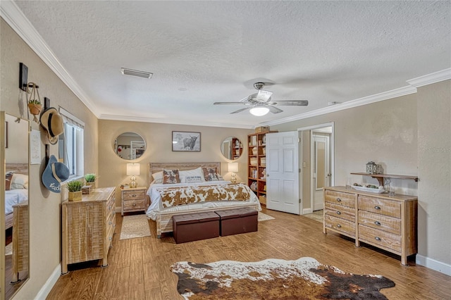 bedroom with light wood finished floors, visible vents, a textured ceiling, and ornamental molding