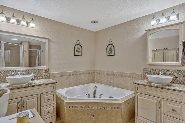 bathroom with a sink, a shower stall, a textured ceiling, a garden tub, and a textured wall