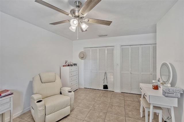 sitting room featuring light tile patterned floors, visible vents, baseboards, and ceiling fan